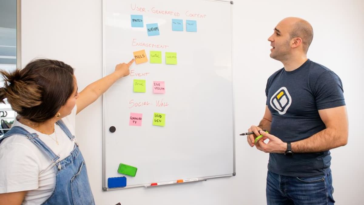 Duas pessoas planejando um processo em um quadro branco com post-its