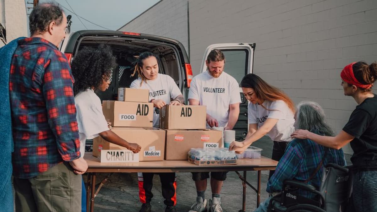 Voluntários organizando caixas de doação ao lado de uma van